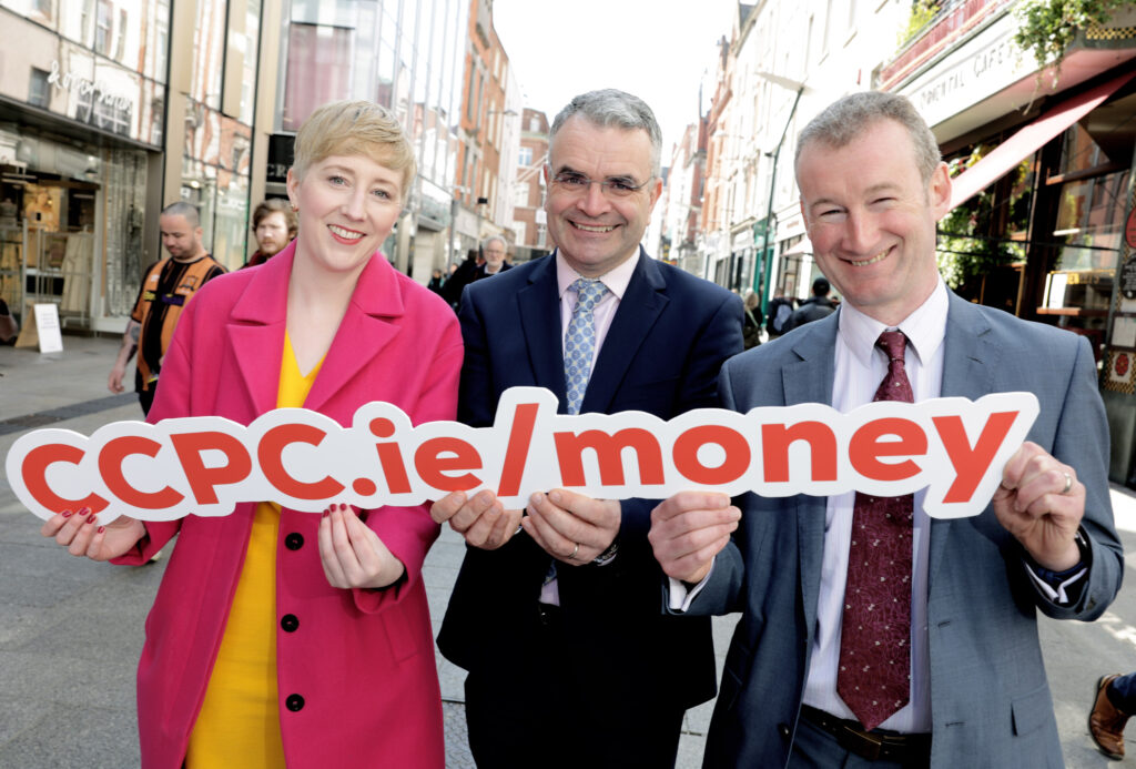 Grainne Griffin, Dara Calleary and Kevin O'Brien holding a sign saying ccpc.ie/money on Grafton street