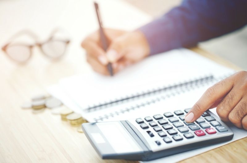 a person using a calculator and writing in a notebook