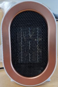 An image of an oval shaped mini heater with black grating and a thick brown/gold rim.