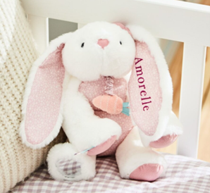 A white and pink rabbit sitting on a chair.