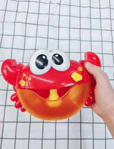 A plastic red crab toy with yellow accents and large white and black eyes. It has an open mouth.