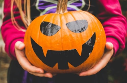 This images shows a child holding Halloween pumpkin