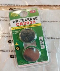 Two button batteries in green package with Whitecrane CR2032 at the top of the package