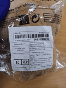 A clear plastic packaging containing a plush toy. The packaging has a white label with black text displaying product details, including a barcode, Chinese characters, and English text such as “Made in China,” manufacturer information, and an email address. 