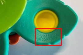 Close-up of a green plastic toy with a yellow circular center. A red rectangle highlights where to find the batch number of the product.
