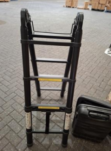 a black telescopic ladder on a warehouse floor