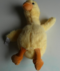 Yellow soft toy duck with orange feet.