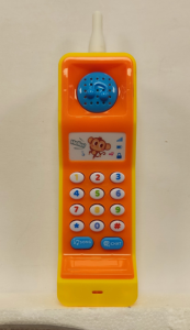 A brightly colored toy phone with a yellow body and orange front panel, featuring a blue speaker at the top, a small cartoon monkey graphic, and a keypad with multicolored buttons, including “Song” and “Chat” buttons at the bottom.