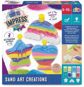 Sand art kit box showing three decorative plastic bottles—a rainbow, star, and heart—filled with colourful layered sand, along with images of sand colours included.