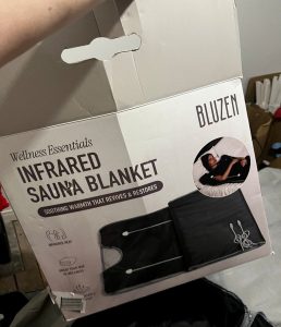 Image shows cardboard box with the words 'Infrared Sauna Blanket', and 'Bluzen' in the corner written on it and a picture of a black sauna blanket.